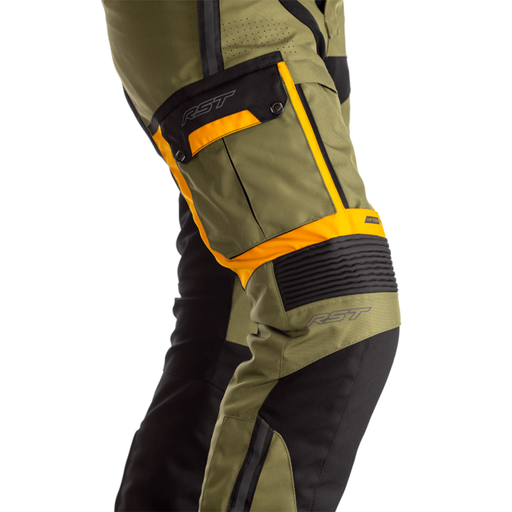Detaljerad vy av RST Textil Mc-Byxor Adventure-X Khaki med orangea accenter och robusta paneler för hållbarhet och stil.